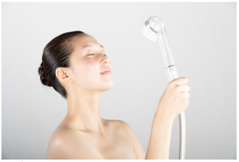 女性がシャワーで顔に水をかけている画像