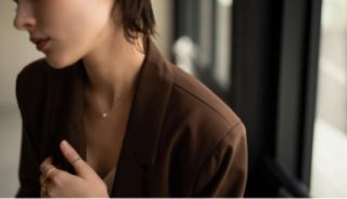 ブラウンのジャケットを着た女性。首もとにネックレスが付ている