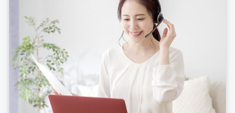 ヘッドセットを付けてノートパソコンを操作している女性