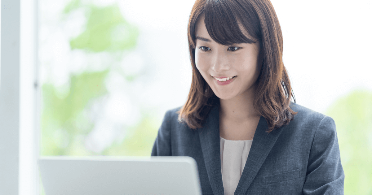 女性がノートパソコンの画面を見て笑っている