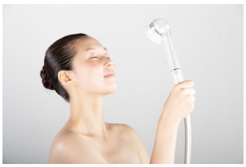 女性がシャワーで顔に水をかけている画像