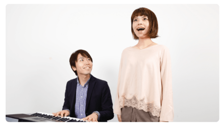 歌をうたっている女性とピアノを弾いている講師